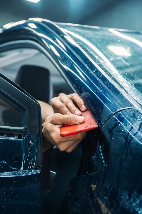 Installer fitting clear paint protection film to a panel edge
